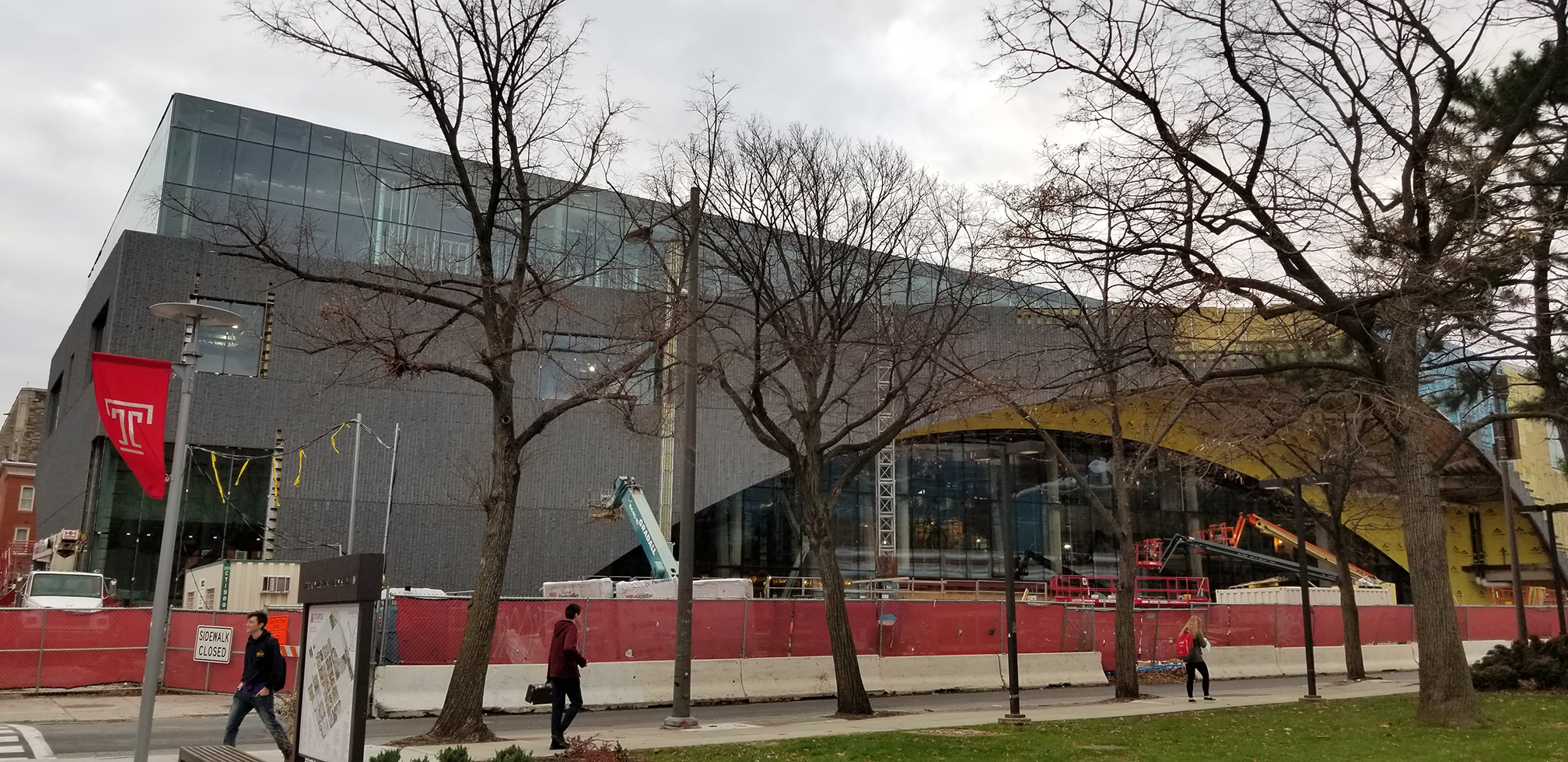 View of modern library with trees and construction barriers in foreground